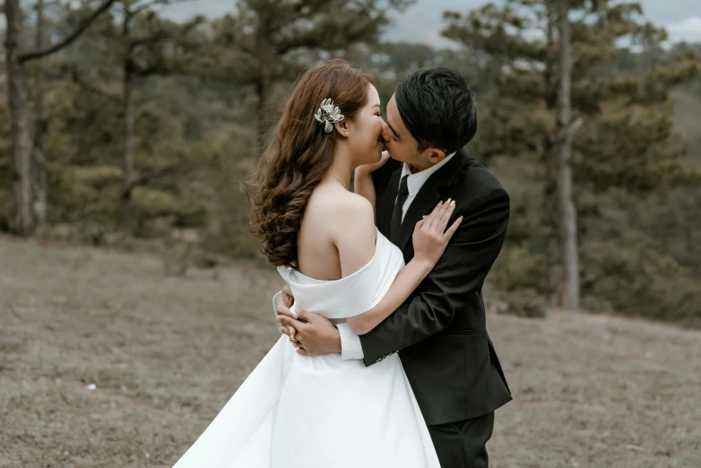 a bride and groom are kissing in front of some trees
