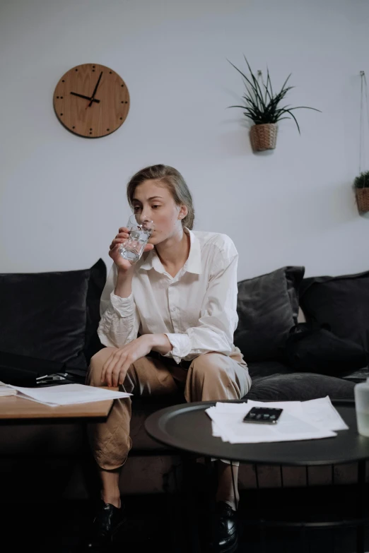 a woman sitting on a sofa drinking water