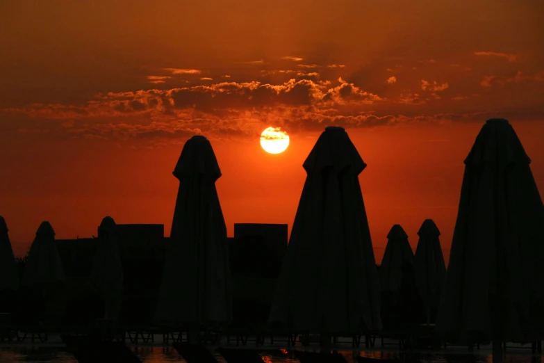 sun setting in the distance over beach umbrellas