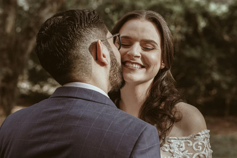 a newly married couple looks loving in a field