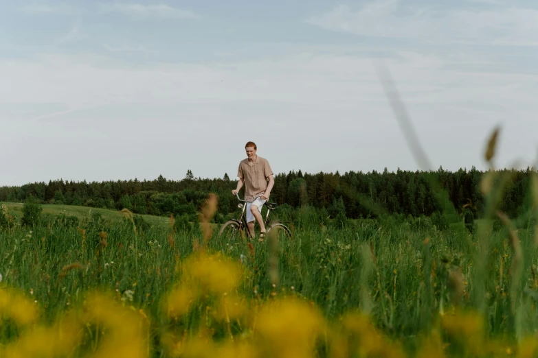 the man is riding his bike through a field of tall grass