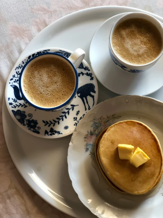 two plates that have food and cups on them