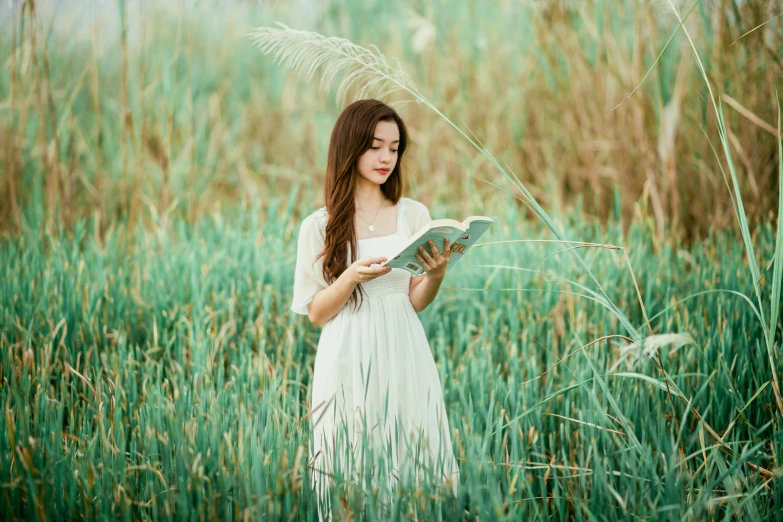 a beautiful woman is reading a book in the grass