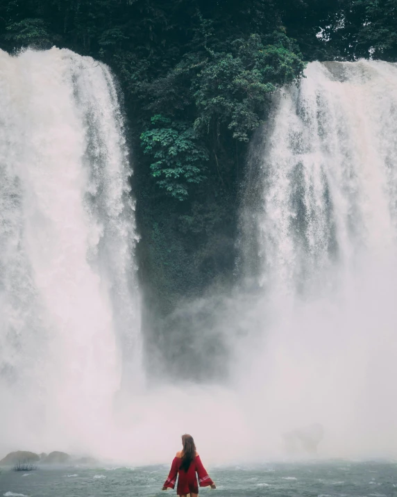 the woman is sitting in front of the water fall