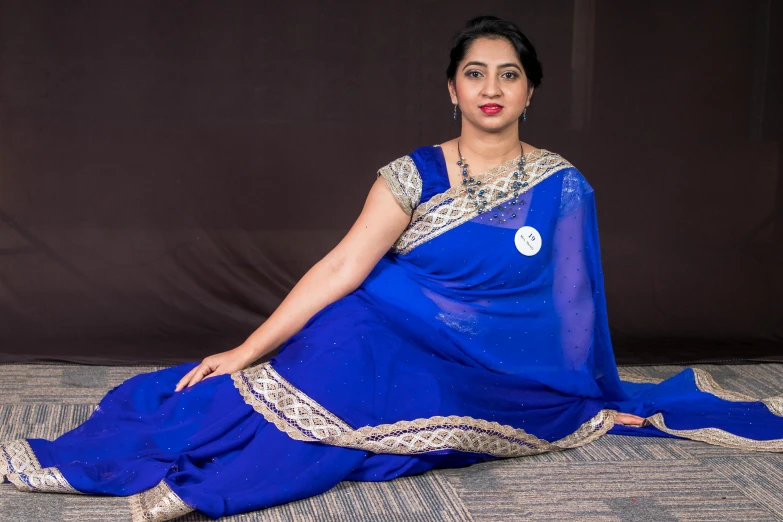 a woman is sitting on the floor wearing a blue sari