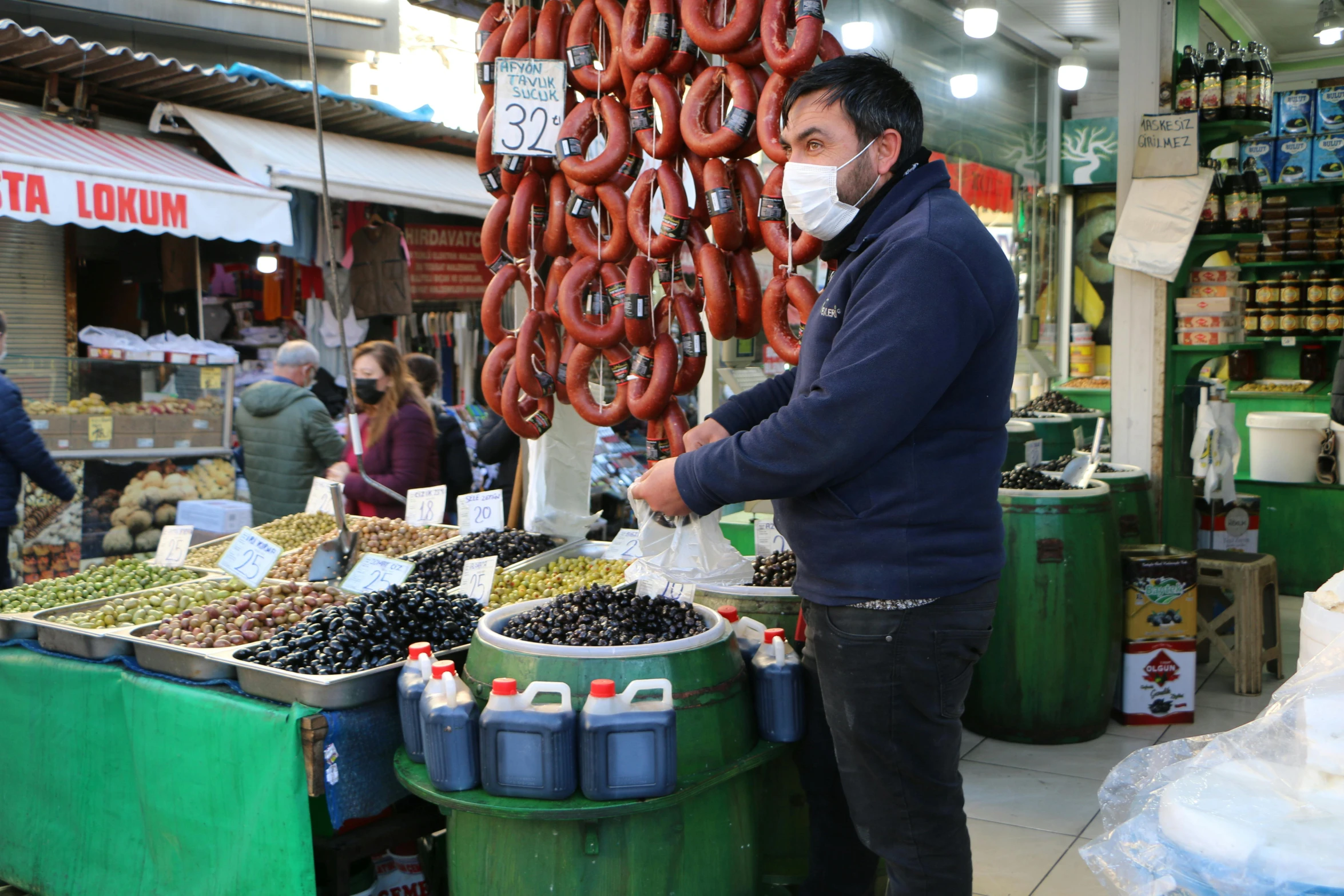 a man wearing a mask stands next to an assortment of food in containers