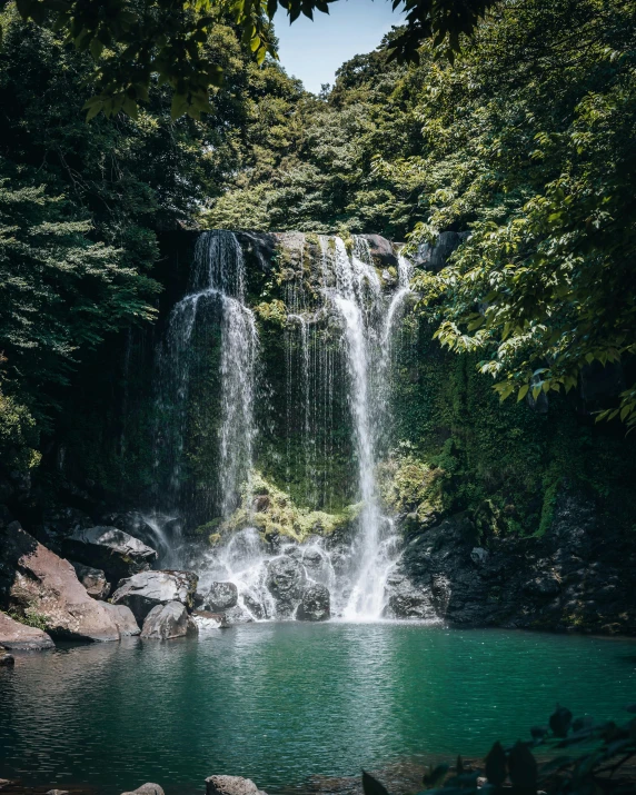 a very tall waterfall is surrounded by green trees