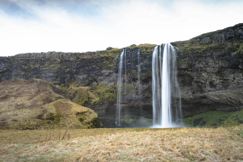 a waterfall is next to some grassy terrain