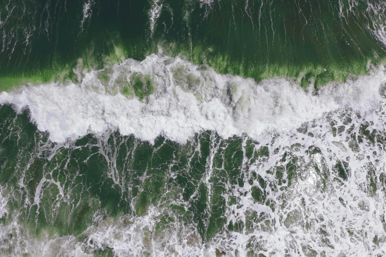 a green ocean water wave next to some rocks