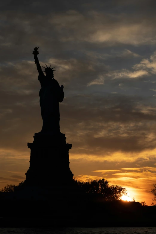 a statue of liberty stands against a cloudy sky