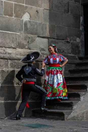 a man and woman in a mexican dress standing on stairs
