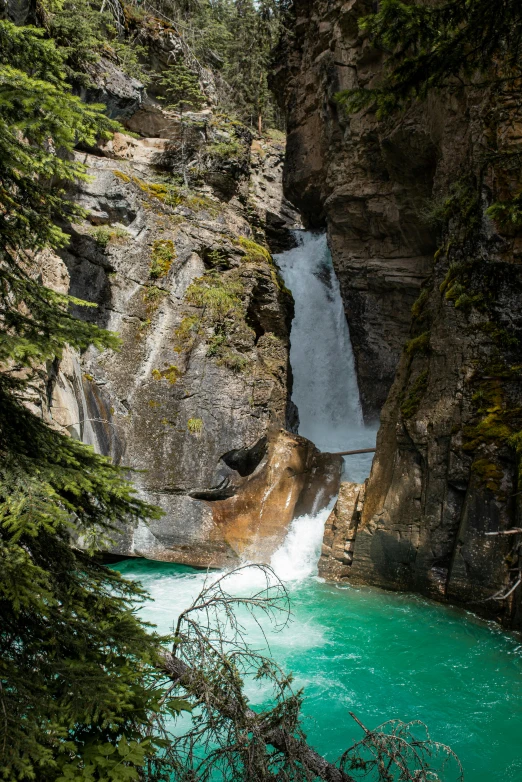 the water flowing from a waterfall into the lake is turquoise