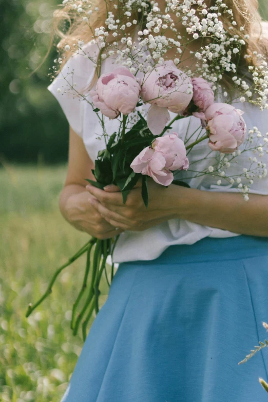 a woman holding flowers in her hands outside