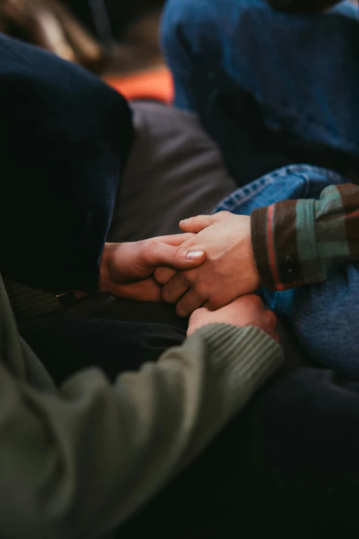 two people hold hands and both sitting on the couch