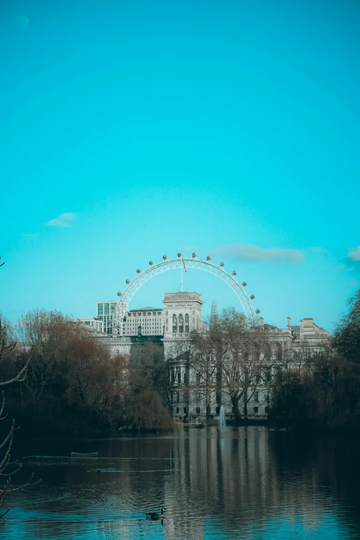 ferris wheel against a blue sky with reflection in the water