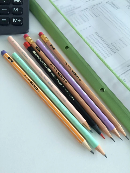 some pencils are sitting on the surface with a calculator