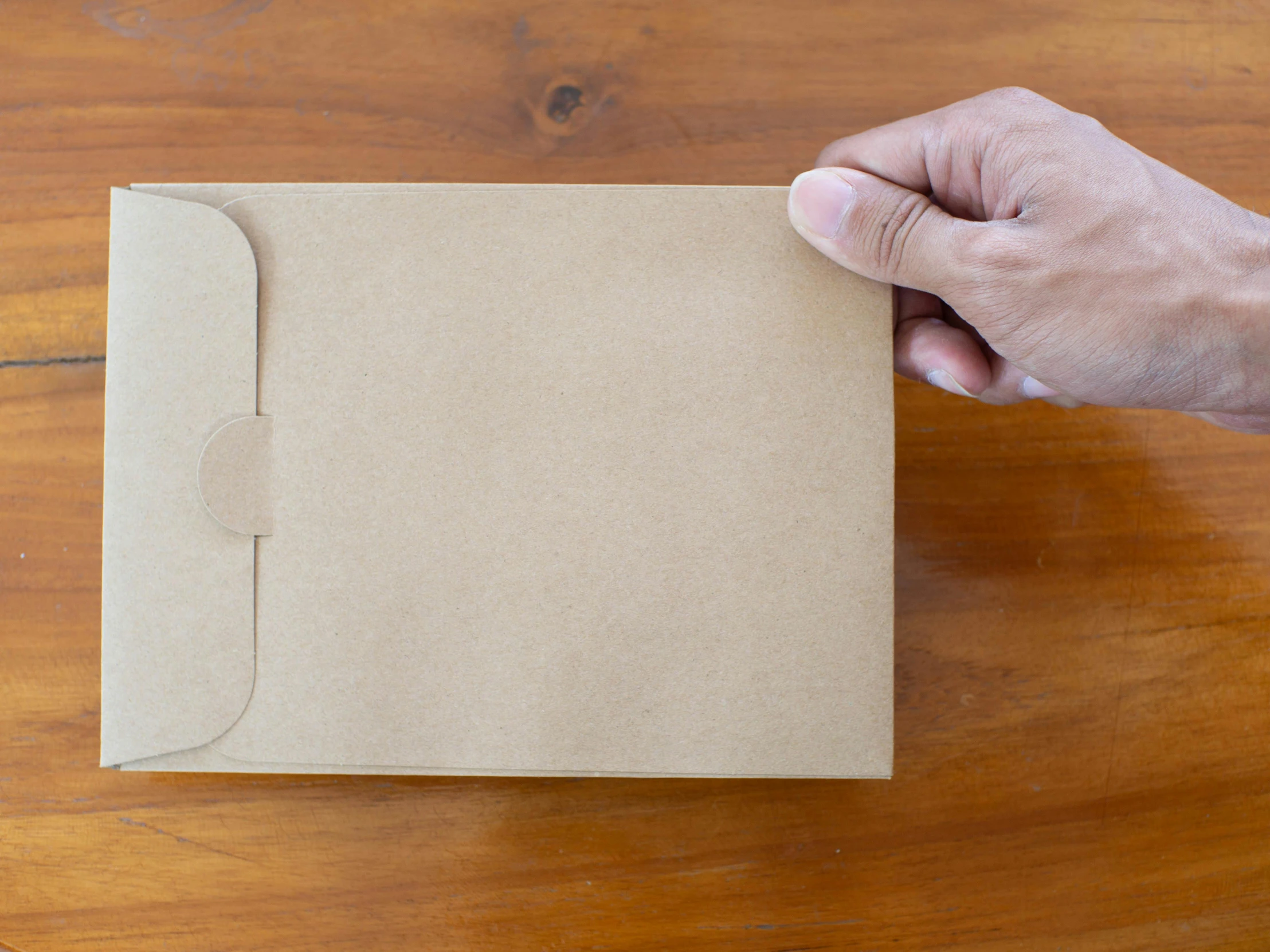 a person holds the brown piece of paper up to place it in front of them