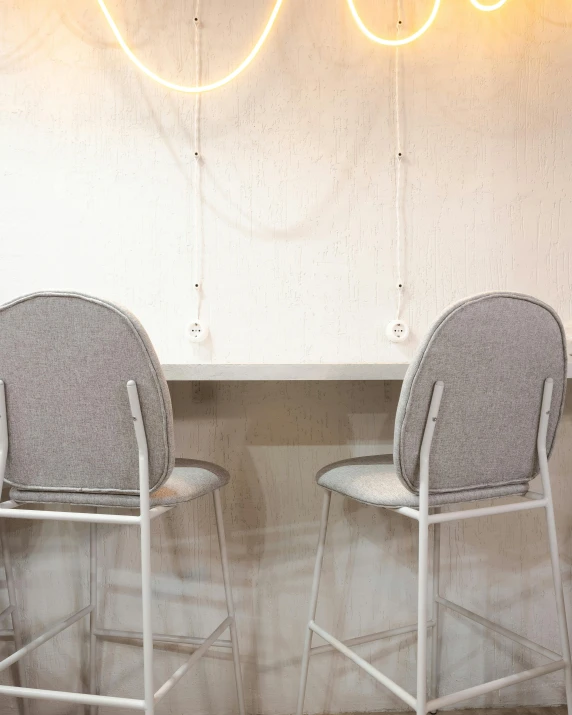 two chairs sitting in front of a wall under a neon sign