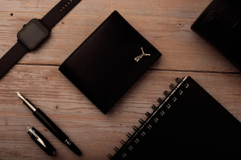 a watch, notepad and pen sitting on a table