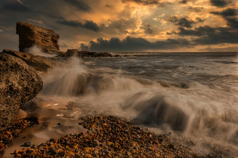 a rock on the shoreline during sunset or sunrise