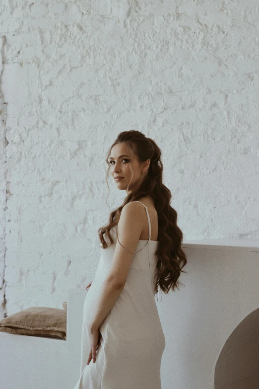 a young woman standing next to an empty wall