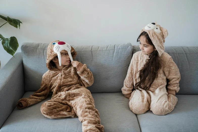 two children dressed up in animal onesuits on the couch