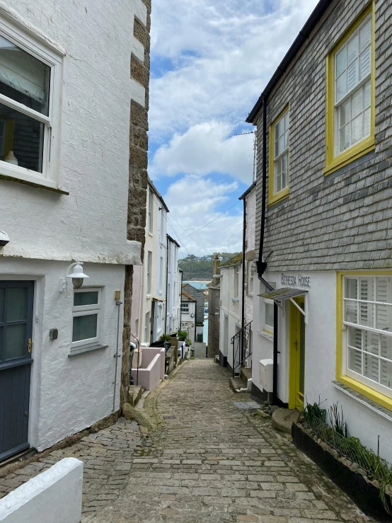 the view of a street between houses with yellow shutters