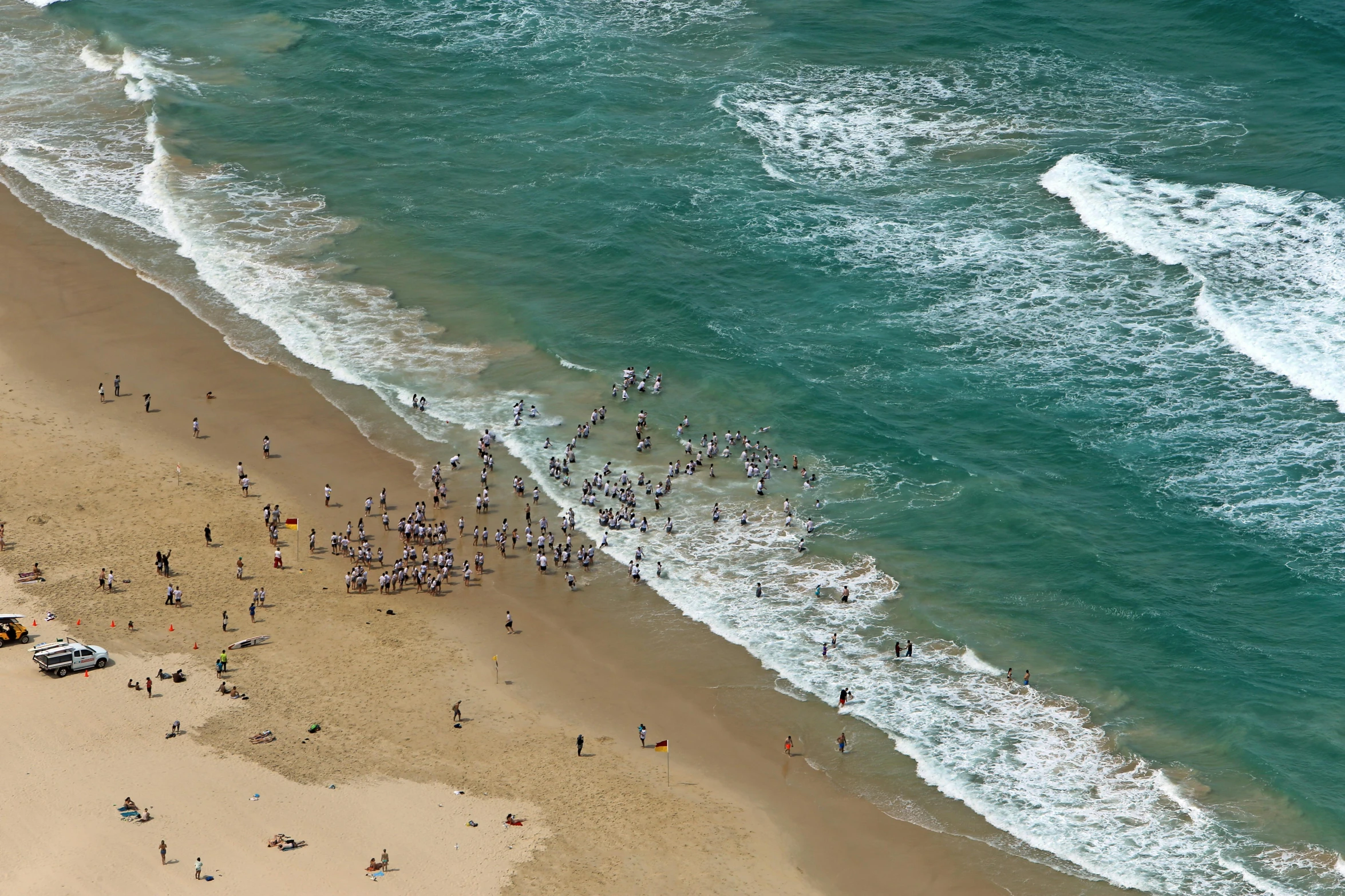 aerial view of a beach with people and trucks