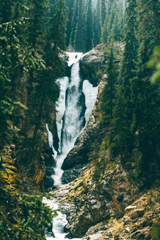 the view of a waterfall that is flowing down a mountain