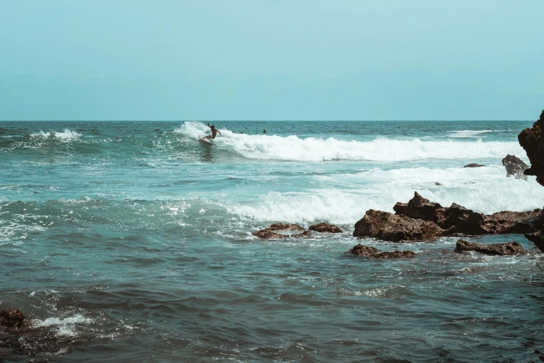 surfers catching big waves off of rocky shoreline