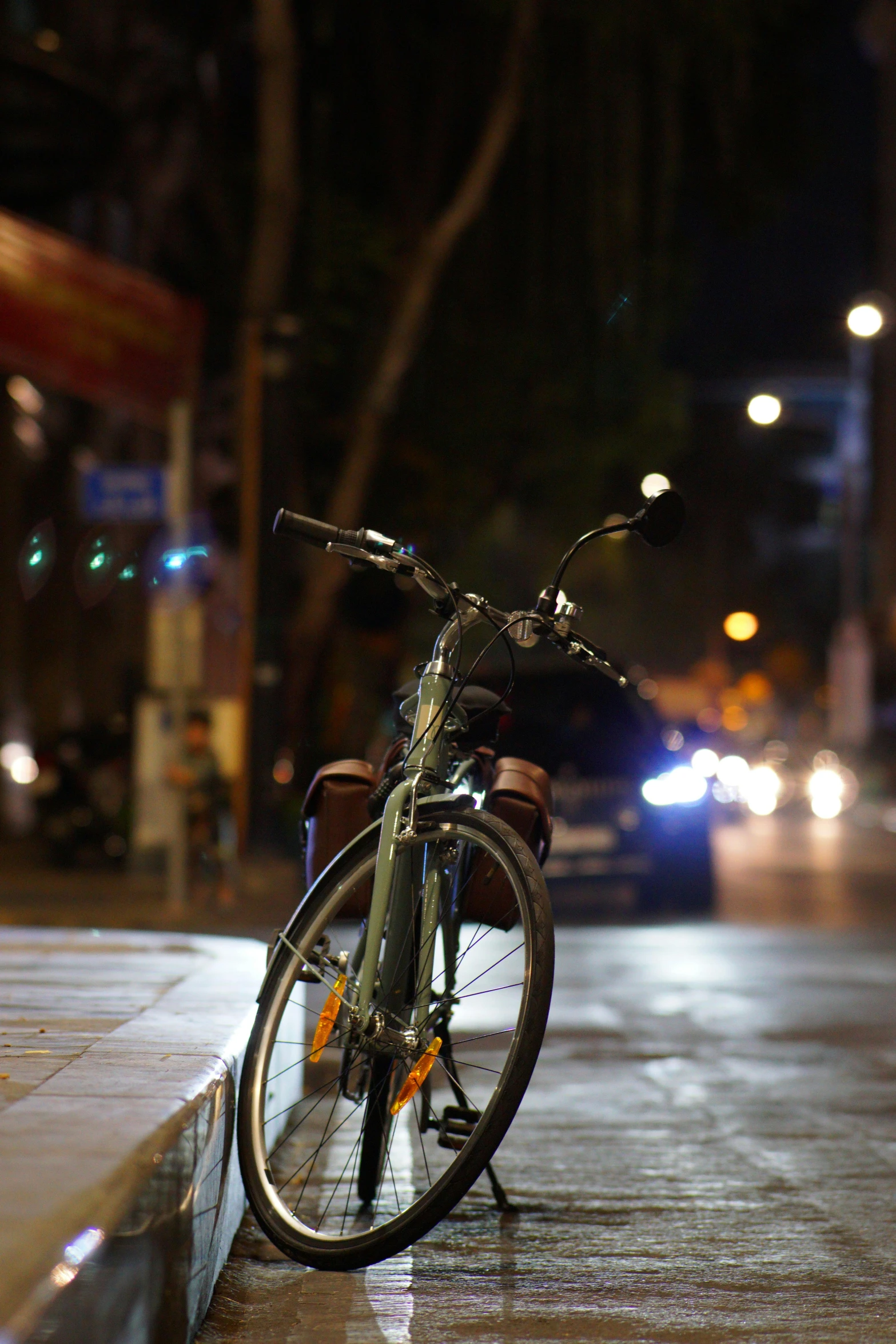 a bicycle  to the side of a curb at night