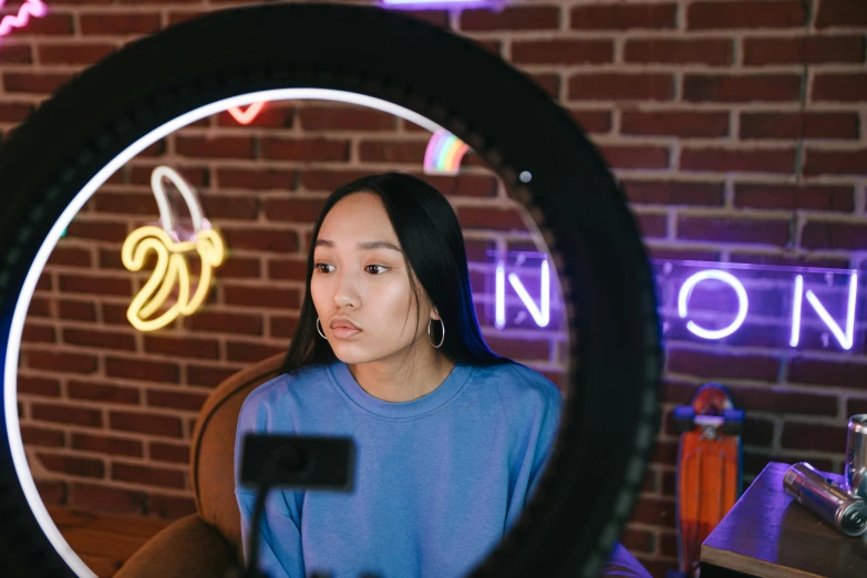 a woman looking through a circular object to a brick wall