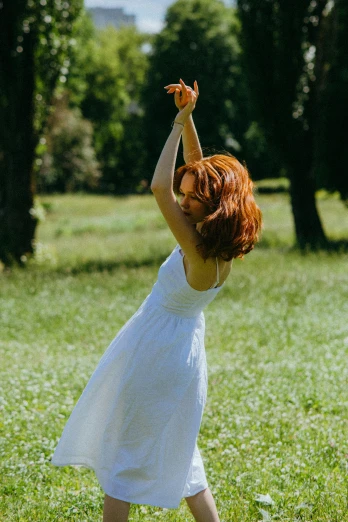 woman in white dress reaching up towards a bird