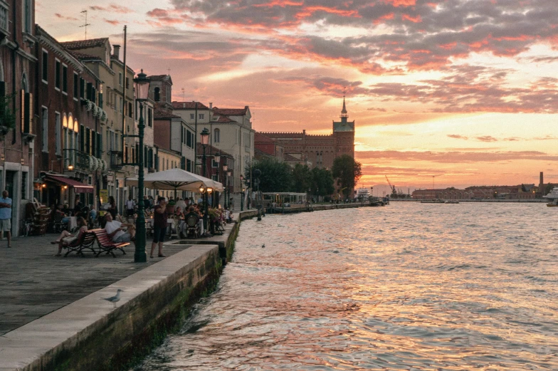 a river scene with sunset in the background and a large building