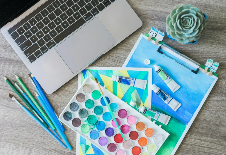 art supplies sit on the table next to a laptop