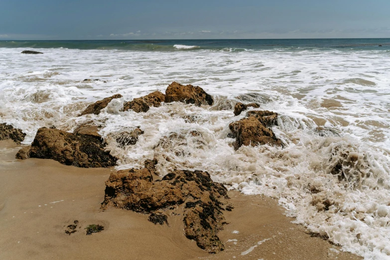 an ocean beach with rocks that have come ashore