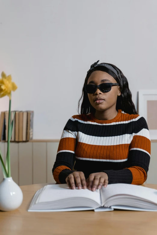 a woman wearing sunglasses and standing in front of an open book