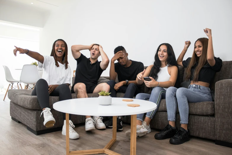 four people sitting in a room, one holding up his fist