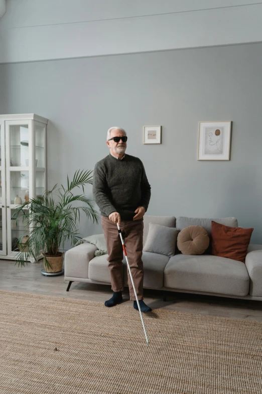 an older man with a cane standing by a sofa