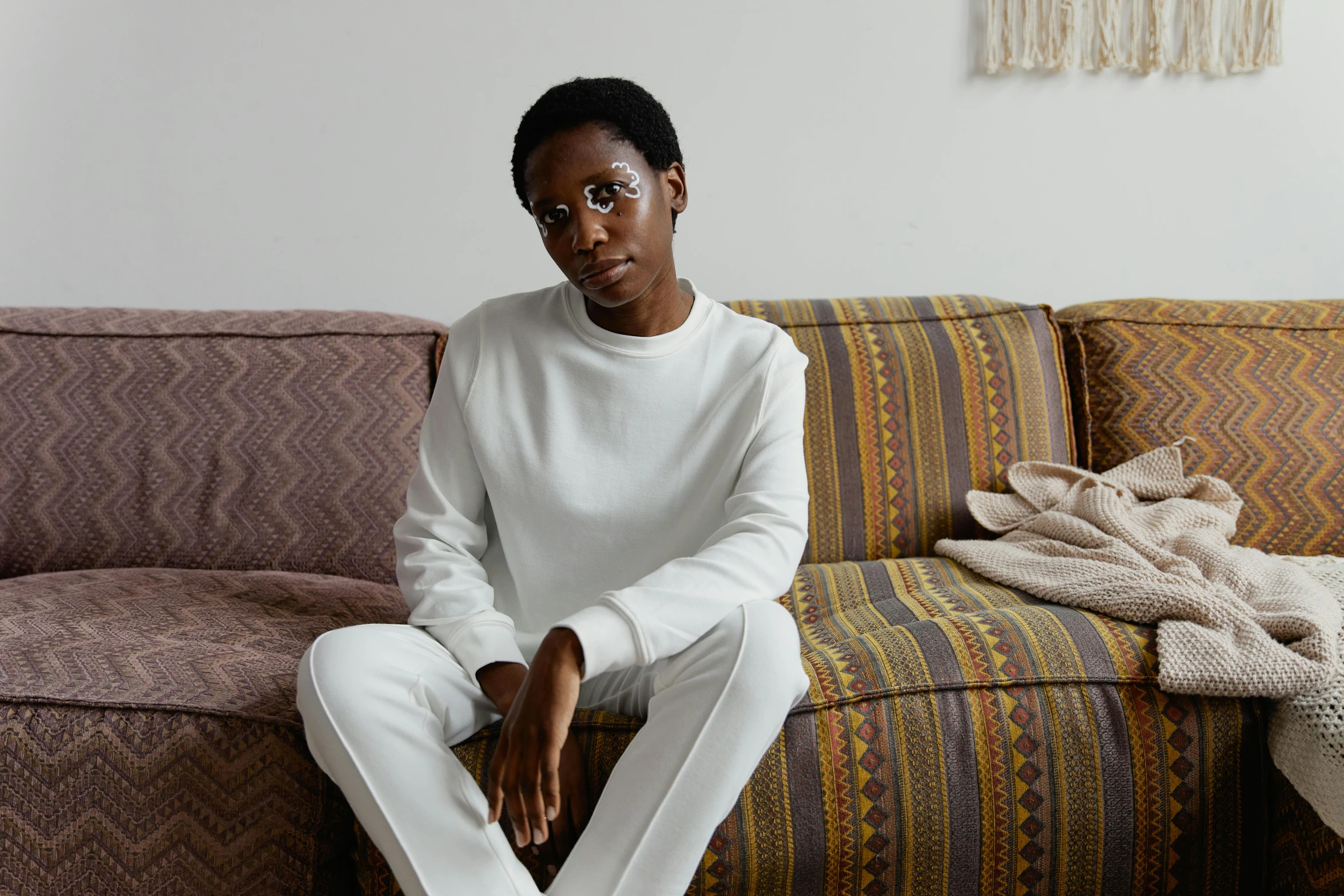 a woman sitting on a couch wearing white clothes