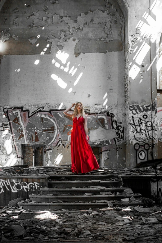 a woman wearing a long red dress is standing on a staircase