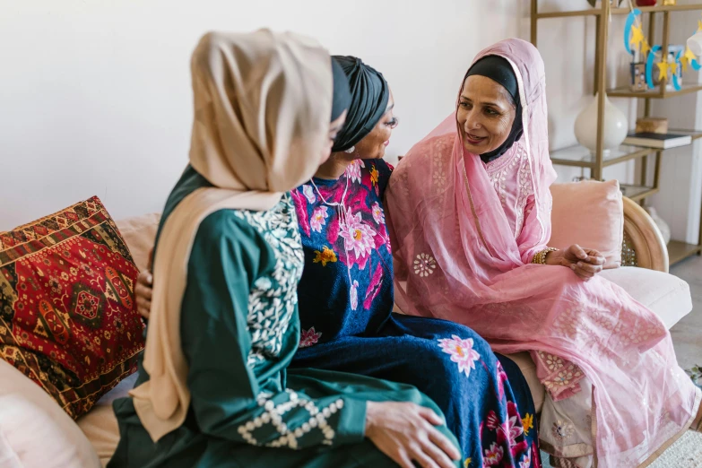 two women in brightly colored hijabs talk in an apartment