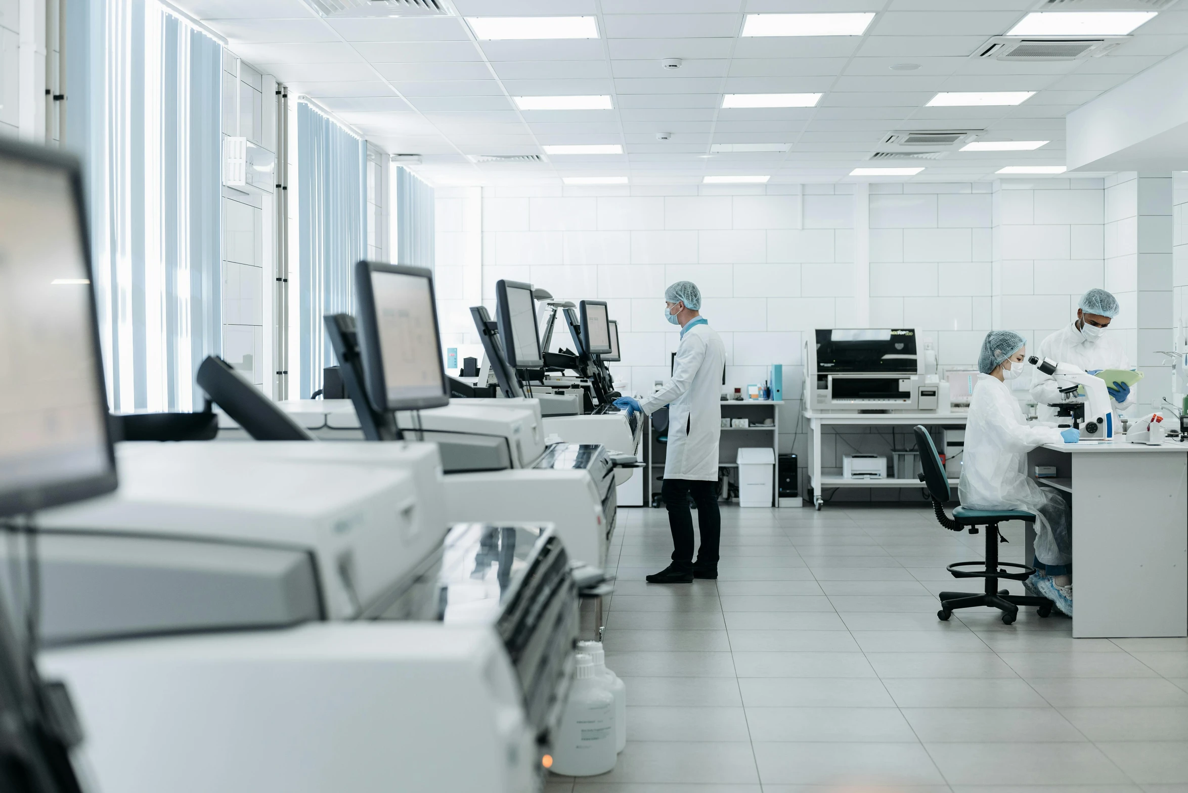 three men in lab coats working on computer monitors