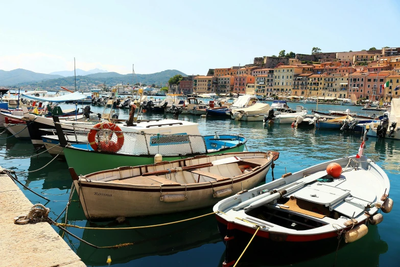 several boats sit parked near a dock, some in the water