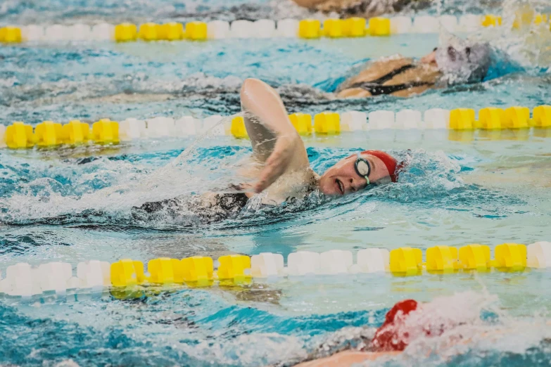 a swimmer wearing goggles and a red hat in the water