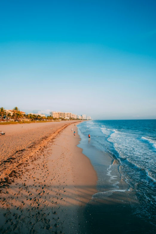 people are walking along the beach in front of a resort