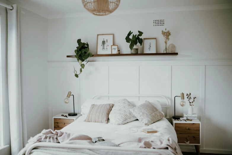 a bed with blankets, pillows and plants on the shelf above it