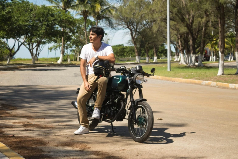 a man is sitting on his motorcycle next to the street