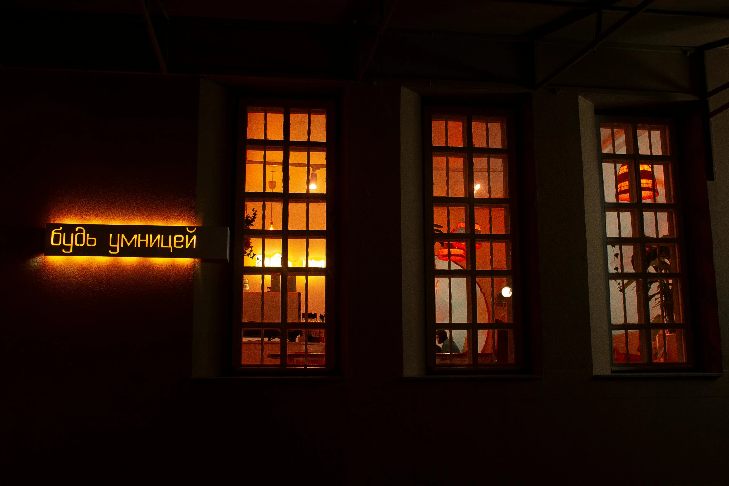 three windows lit up by neon lights in a dark room