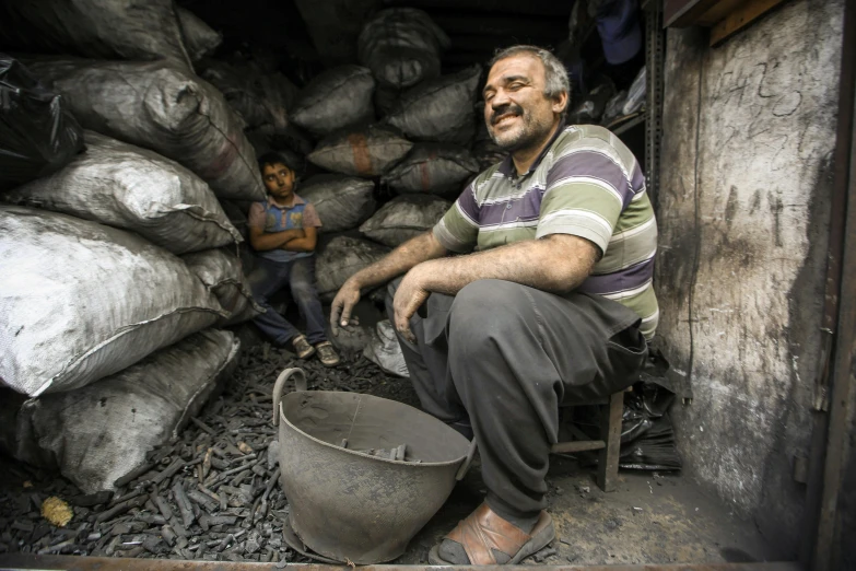 a man is sitting down near some bags of gravel